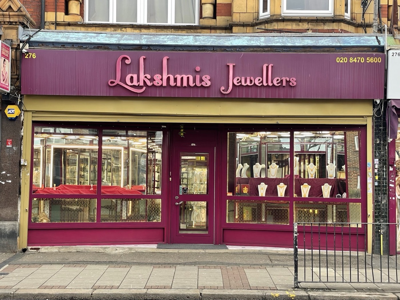 The maroon and gold shopfront of Lakshmis Jewellers at 276 High Street North, East Ham, windows filled with gold jewellery
